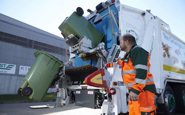 Mitarbeiter leert Grüncontainer in Ghüderwagen