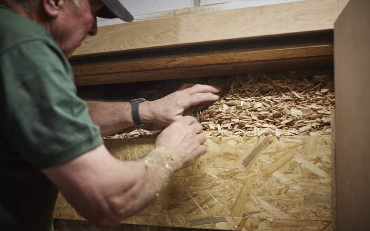Handwerker füllt Holzschnitzel in die Heizungsanlage
