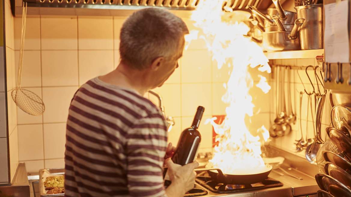 Koch flambiert das Essen mit Wein