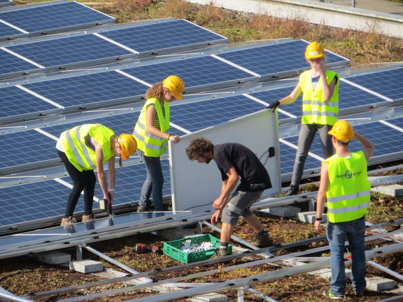 Schüler installieren Sonnenkollektoren auf dem Dach
