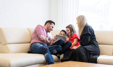 Familie Simic mit Tablet auf dem Sofa